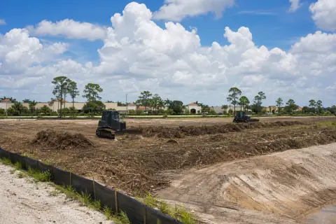 Commercial clearing limits marked beside retained pines and a stabilized construction entrance